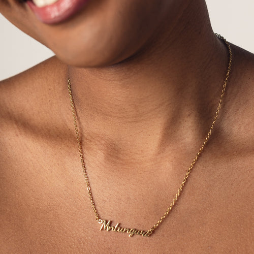 Close-up of a person's neck wearing an 18k gold plated necklace with the word "Mntungwa" spelled out in cursive letters.