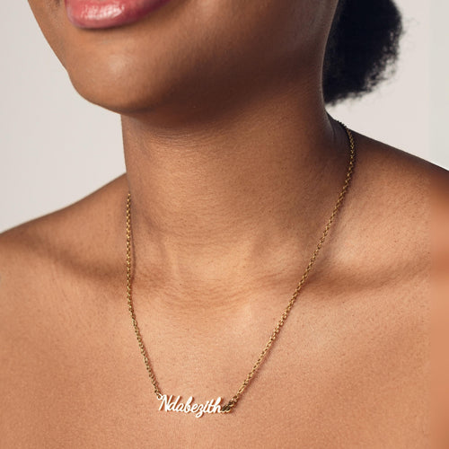 Close-up of a person's neck wearing an 18k gold plated necklace with the word "Ndabezitha" spelled out in cursive letters.