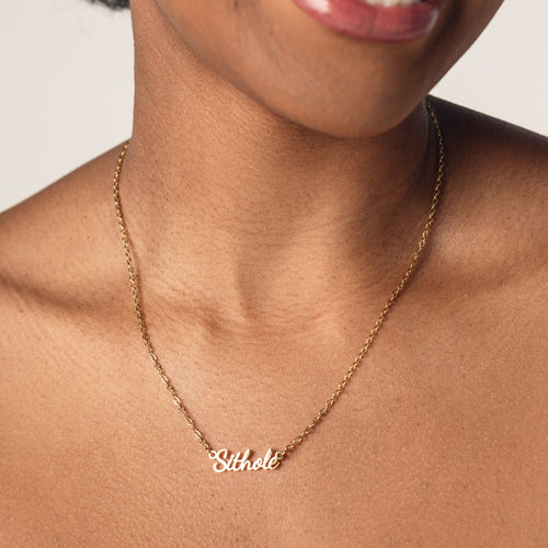 Close-up of a person's neck wearing an 18k gold plated necklace with the word "Sithole" spelled out in cursive letters.