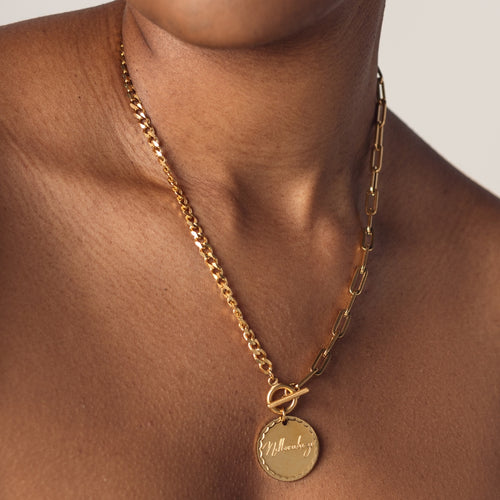 A close-up image of a woman wearing a 18K gold plated chain necklace with a round pendant engraved with "Ndlovukazi"