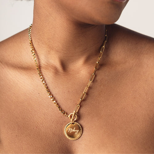 A close-up image of a woman wearing a 18K gold plated chain necklace with a round pendant engraved with "Ntokazi"